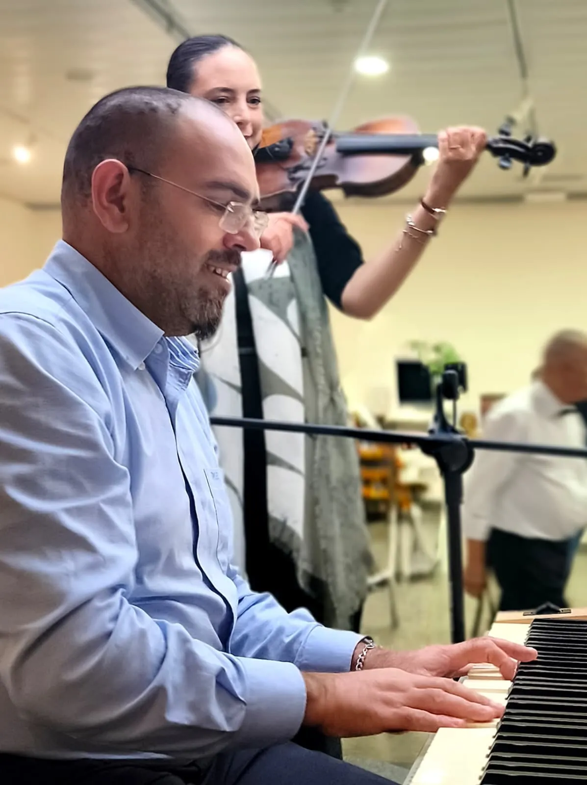 O Nelson ao piano e a Joana ao violino atrás dele, a tocar num evento
