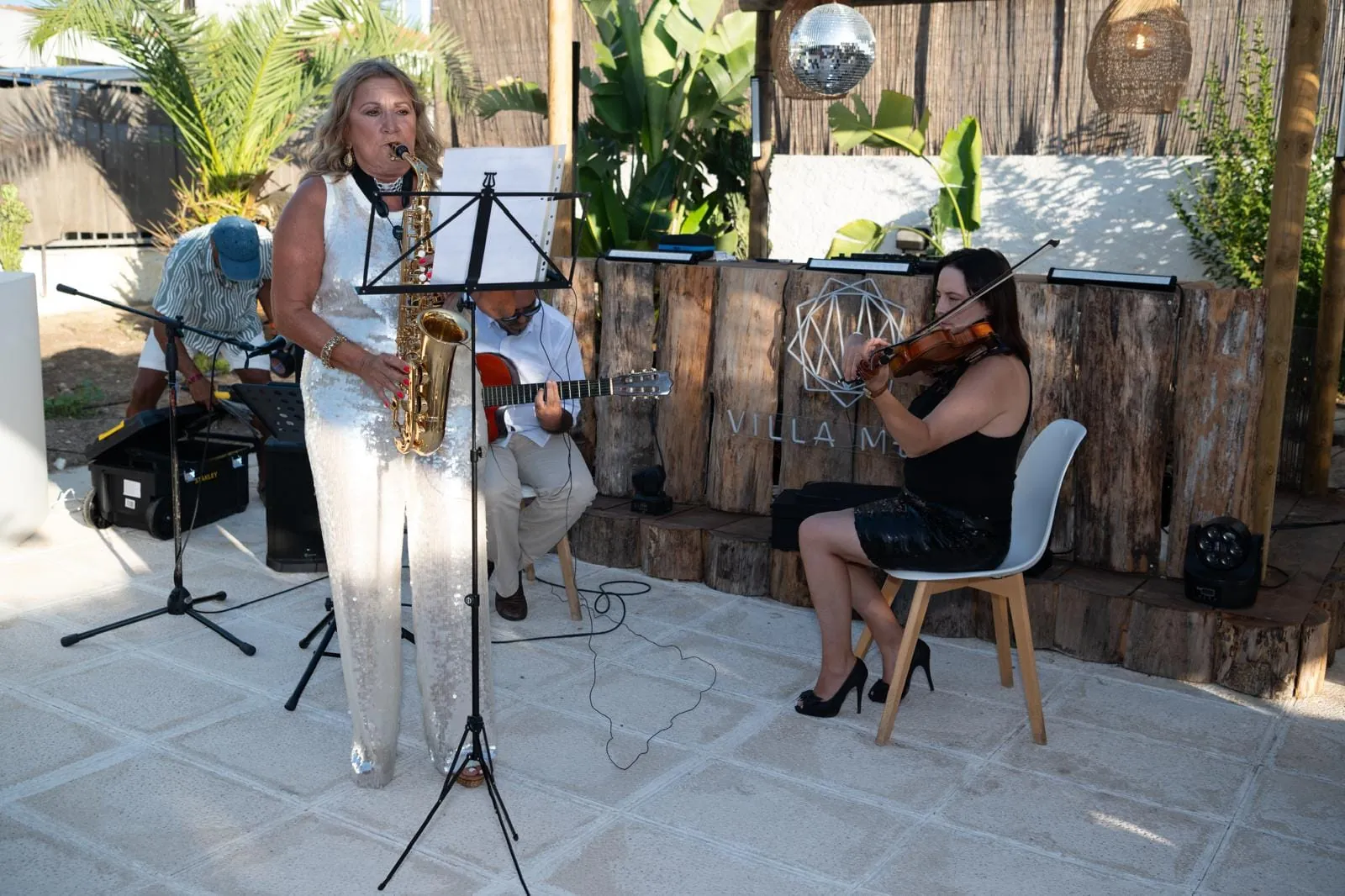 Saxofone, voz, guitarra e violino a tocar num pátio na Villa Meco